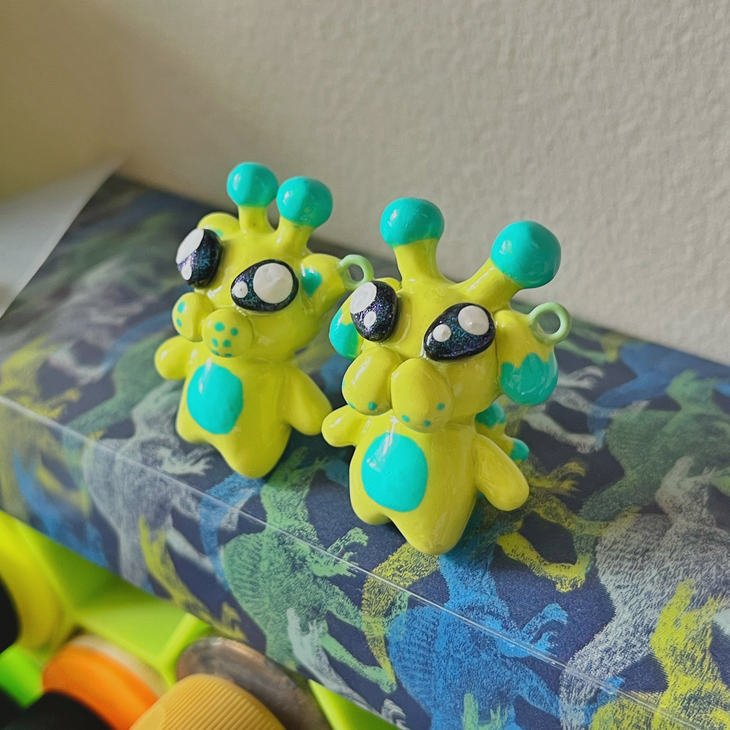Two green alien figurines with blue accents on a colorful surface.